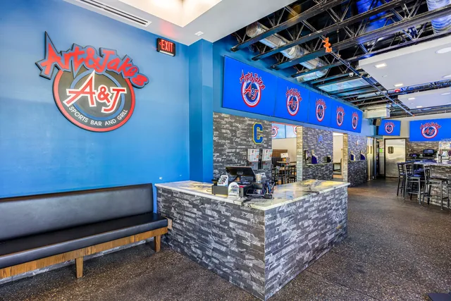 The Clarkston bar under the Art & Jake's logo wall, screens on above the taps
