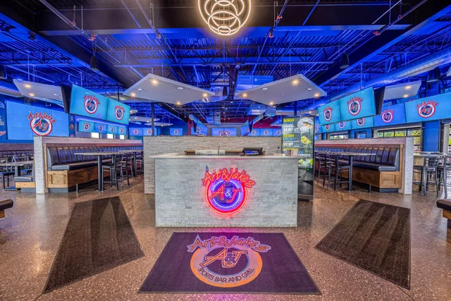 The Lansing bar lit blue, the round Art & Jake's logo above the back counter